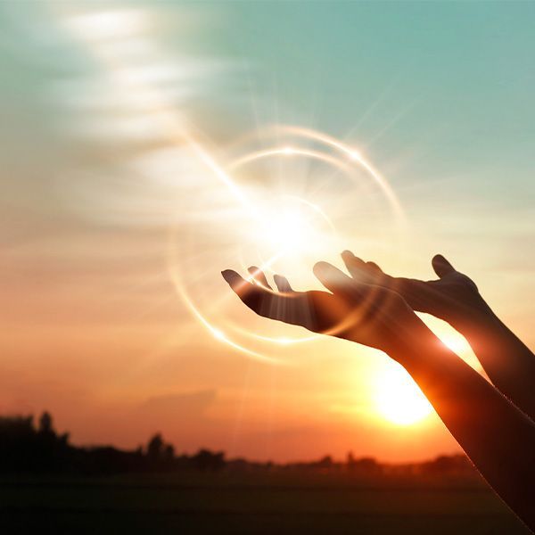 A person is reaching for the sun in their hands. 